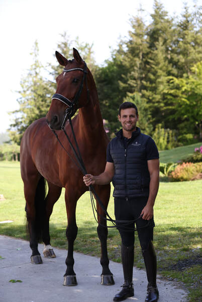 Aaron Janicki standing beside a dressage horse at the farm